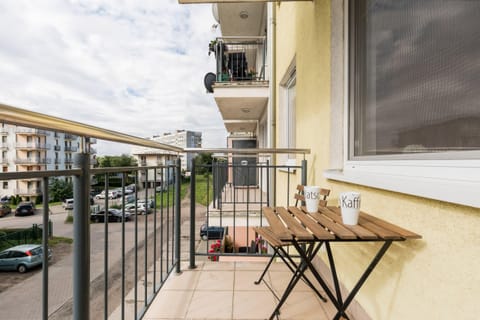 A small outdoor balcony with a table and two chairs, perfect for enjoying a coffee while overlooking the view outside.