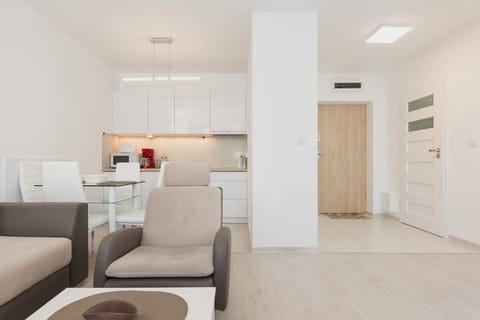 Functional living room with double sofa bed, coffee table, television, armchair, dining table, and kitchenette.