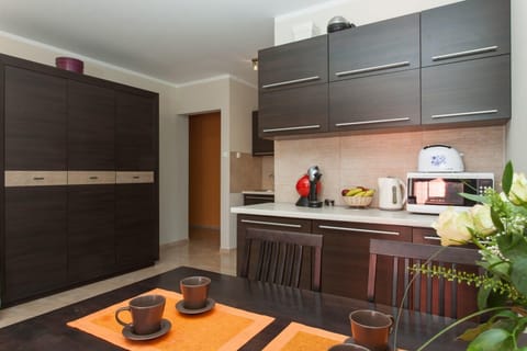 Another view of the kitchen from a different angle, highlighting the appliances and dark wood cabinets. A small dining table is set nearby for convenience.