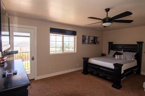 Queen bed in main room shows balcony access, view of the Tacit Shadow yard.