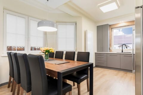 A dining area connected to a living room, featuring a wooden table with four chairs and an open, spacious design.