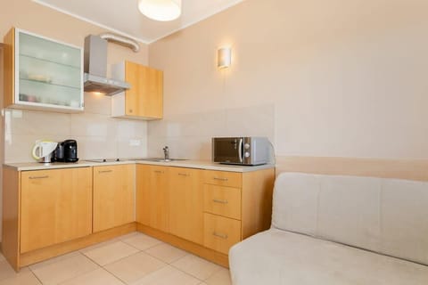 A compact kitchen with light wood cabinets, white countertops, and basic appliances. Simple and practical design.
