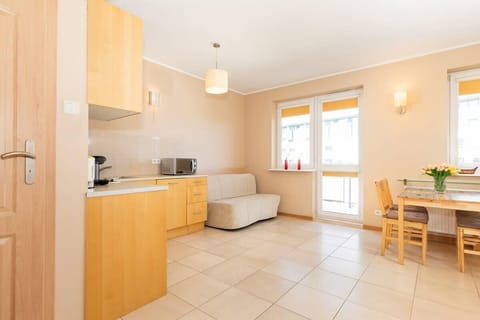 Another living room angle, showing a sofa, coffee table, and a wooden dining table. The room is spacious and filled with natural light.