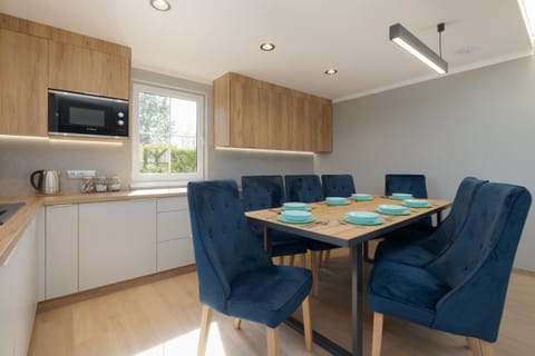 A sleek kitchen with wooden countertops and contemporary appliances, blending style and functionality, with a cozy dining nook visible in the background.