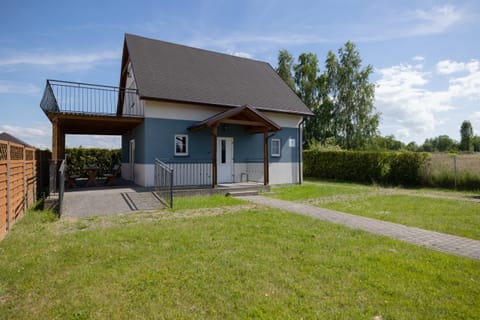 A cozy country house with a sloped roof and wooden accents, surrounded by a lush green lawn, perfect for a peaceful retreat in nature.
