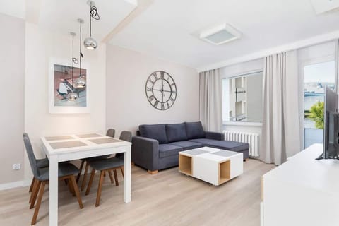 A cozy living room with light-colored furniture, a coffee table, and a large window that fills the space with natural light.