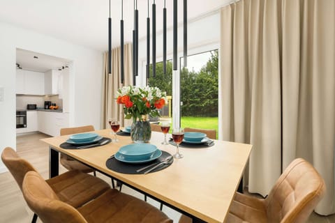 The wooden table set with tableware and fresh flowers invites guests to share meals in the bright dining area.