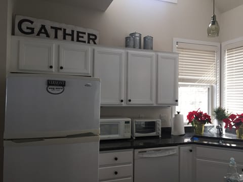 Clean, stocked kitchen with gas stove, peninsula and large table with benches.