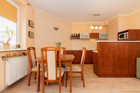A wooden dining table with four chairs sits in a light-filled room. A window nearby provides natural light, creating an inviting dining space.