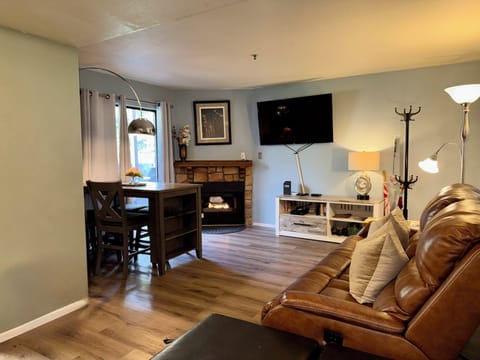 Living room with gas fireplace, reclining leather couch and Roku TV 