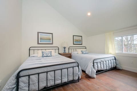 Spacious bedroom with two cozy beds, natural light, and charming coastal decor.