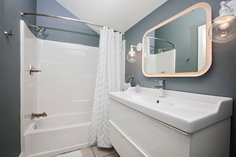 Bright and stylish bathroom with a full tub, glowing vanity, and sleek finishes.