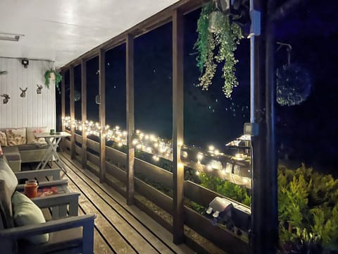 Unwind on the covered porch with a glass of wine, cosy seating and soft lights overlooking the water - the perfect spot to relax after a day of exploring | Harperfield Chalet, Lanark