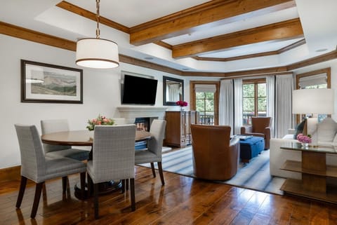 Dining area with round wood table and gray upholstered chairs under a drum pendant light.