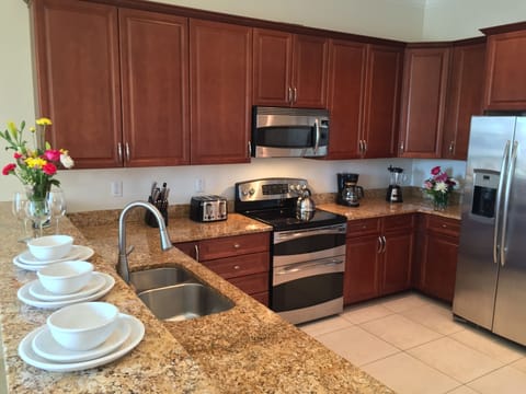 Kitchen with granite counters, hard wood cabinets, and stainless appliances.