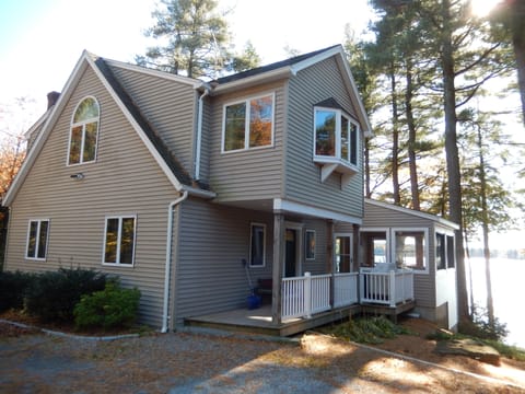 House in fall with covered porch entrance, screen porch on right, grill on porch