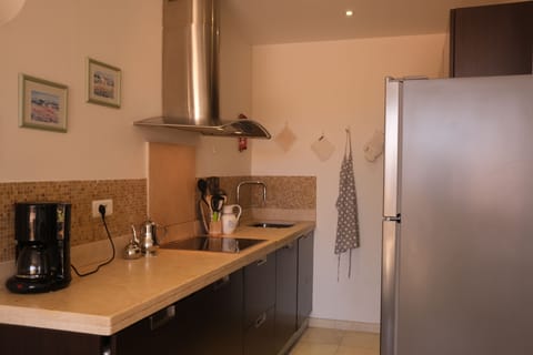 Kitchen with electric hob, marble work-top, fridge, oven and microwave.