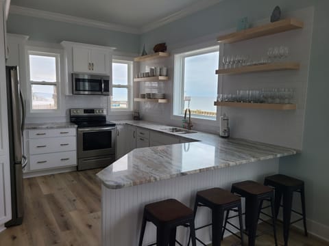 View of kitchen, granite counters.  Ice maker in fridge. Bar seating for 4.