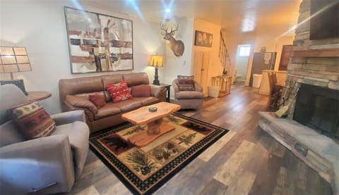 Unwind in your spacious living room with plush seating, rustic stone fireplace, and warm wood floors—perfect for cozy evenings after mountain adventures.