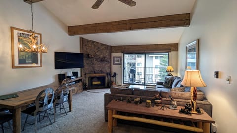 Living room with sofa bed, wood fireplace, dining table, and balcony w/ gas BBQ