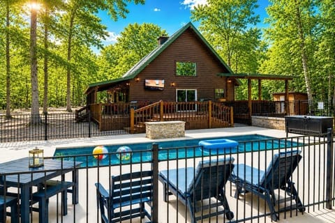View across the pool, to cabin deck with seating and covered hot tub