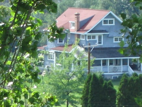 Large shady front porch seen through the trees