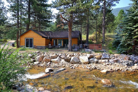 View of side of cabin from across river. Patio, hot tub, fire pit, gas grill.