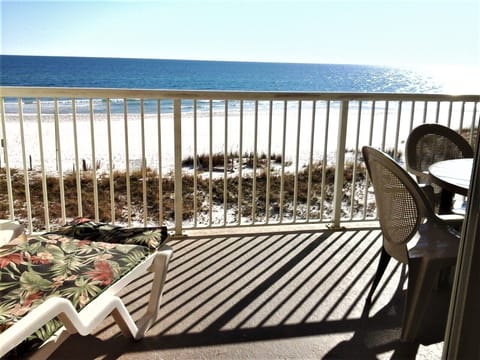View from gulf-front balcony with chaise lounge and outdoor dining