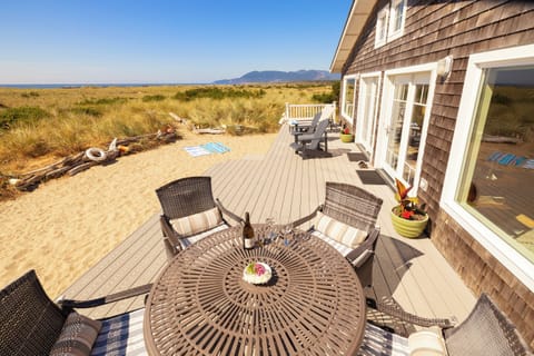 Large oceanfront deck with sandy play area, outdoor table & deck chairs
