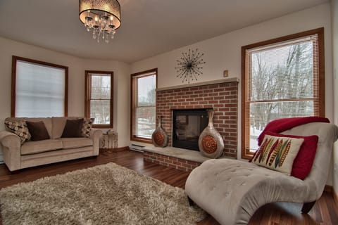 Relaxing room, red brick gas fireplace, couches, lounge chair, lots of light