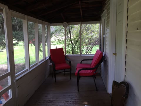 The screened in porch is shaded by two huge spruce trees.