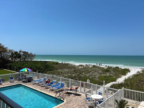 View of pool area with several beach chairs and umbrellas with tables to access!