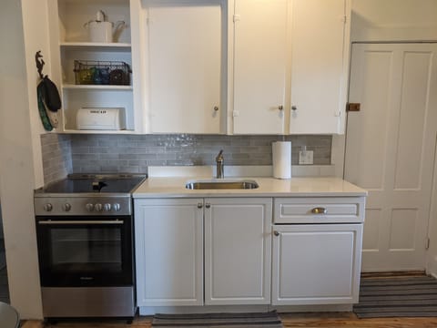 Kitchen sink area with new stove, quartz counters and ceramic backsplash.