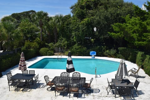 Pool area with 3 metal tables, umbrellas, and chairs