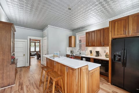 Cozy kitchen with wood cabinets, island seating, and a charming tin ceiling.