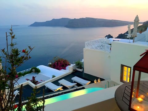 Relaxed lounging at sunbathing terrace by the pool. Caldera view at sunset time.