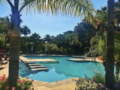Pool view with loungers that sit in the pool with views of lush,tropical gardens