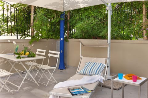 Patio with sun beds, beach umbrella, hot shower.
