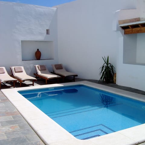 Private swimming pool with four sun loungers and a covered area for BBQs