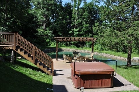 Hot tub and outdoor seating by pond.