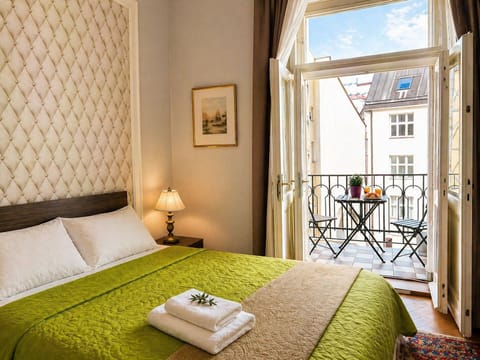Bright bedroom with balcony breakfast, green bedding and quiet courtyard view.