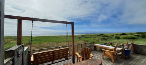 Large oceanside deck with porch swing, dining table, hammock chair and bbq grill