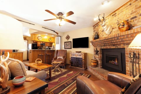 Settle into this warm living room with its inviting leather seating, rustic brick fireplace, and charming touches that make your mountain retreat feel like home.