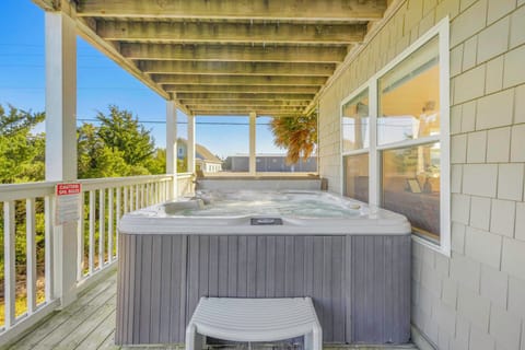 Unwind in your private hot tub on the covered deck, surrounded by lush greenery and coastal charm.