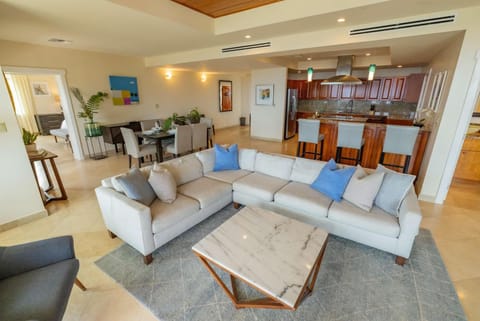 Light-filled living room with a gray sectional, marble coffee table, and open views into the dining area and kitchen.