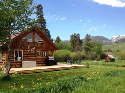 Grpa's cabin side yard, entrance to cabin, log playhouse, fire pit, and creek