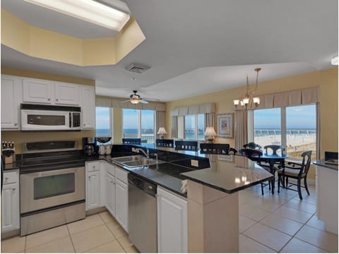 Your fully equipped kitchen opens to stunning beachfront views through floor-to-ceiling windows, creating the perfect space for memorable meals.