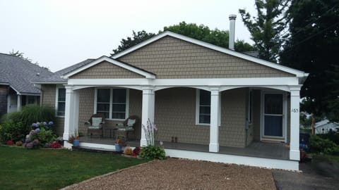 Front of house with porch and chairs for relaxing. Beautiful flowers in season.