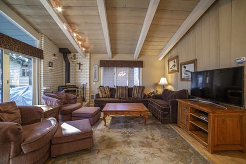 Expansive living area with flat screen television and woodburning fireplace