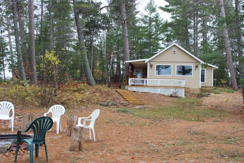 Cottage sits above fire pit among tall norway pines and overlooks Lake Superior